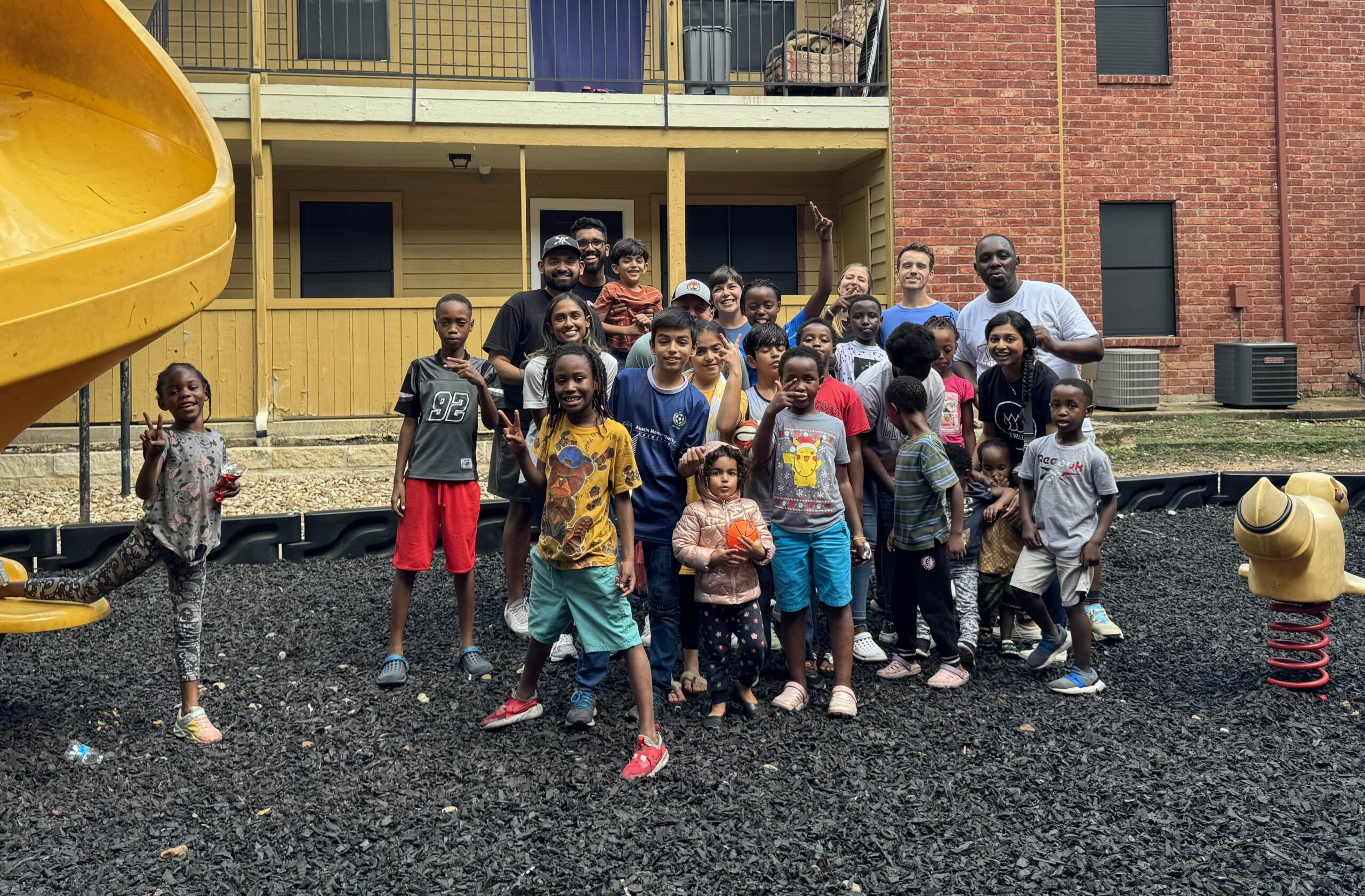 Refugee kids and families on a playground with volunteers